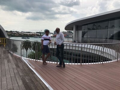 Two people standing on a wooden deck with a modern building in the background